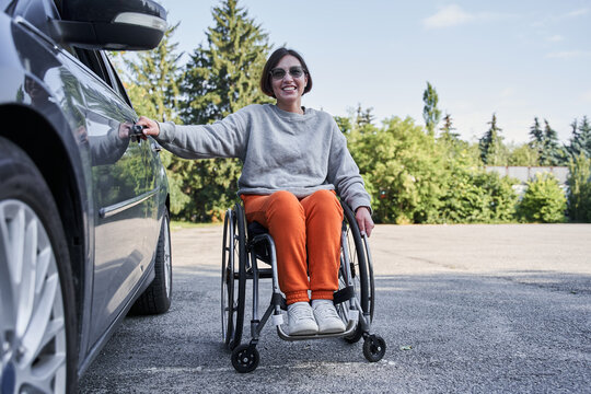 Disabled woman on wheelchair boarding a car door during the sunny day