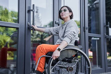Physically challenged girl moving herself at the wheelchair and opening doors