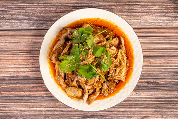 The cooked spicy chicken on a plate is on the wooden table