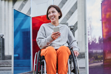 Woman looking away and holding her smartphone while sitting at the special armchair