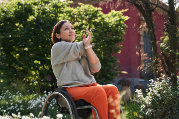 Brunette girl with loss of leg function sitting at the wheelchair and stretching her arms