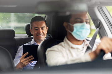 Fototapeta na wymiar transportation, health and people concept - happy smiling male passenger with tablet pc computer and indian taxi driver wearing face protective mask for protection from virus disease driving car