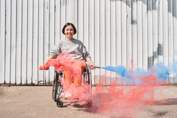 Girl with loss of leg function sitting at wheelchair and playing with bombs with smoke