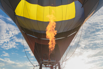 Hot flame from a gas burner light up inside of a hot air balloon at evening.