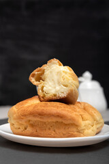 Profiteroles with curd filling. Homemade baking for tea. Dessert eclairs on black background. Close up