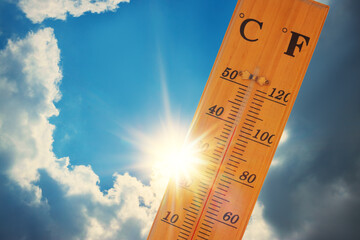 Thermometer, blue sky with clouds, bright sun.  The heat. Hot summer day.