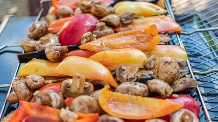 Vegetables on the grill close-up. Eggplants, peppers, mushrooms and garlic are roasted over charcoal. Vegetarian grill.