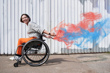 Girl with loss of leg function moving herself at the wheelchair and smiling
