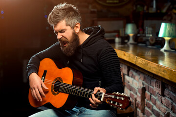 Handsome man with guitar singing songs at bar. Man play guitar in pub.