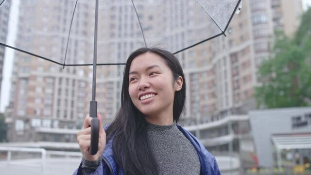 Young asian woman dancing and jumping in rain, feeling positive, slow motion