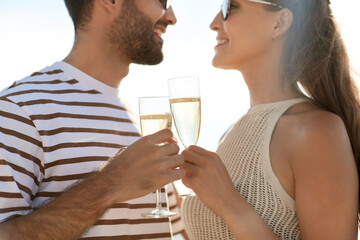 leisure, relationships and people concept - happy couple in sunglasses drinking champagne on summer beach