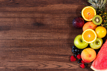 Frutas varias, manzana, kiwi, piña, sandia, frambuesa, mora, naranja sobre una mesa de madera natural y rustica .