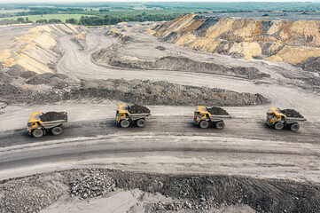 Large quarry dump truck. Big yellow mining truck at work site. Loading coal into body truck. Production useful minerals. Mining truck mining machinery to transport coal from open-pit production © timofeev