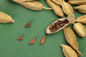 Cardamom fragrant spice seed closeup macro on green paper background