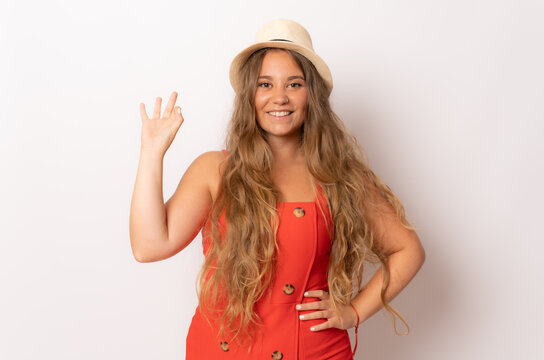 Smiling young woman in straw hat with okay sign gesture isolated over white background.