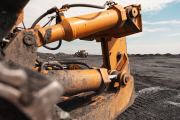 Yellow excavator in career moves overburden. Bulldozer combs the ground, with the bright sun and nice blue sky in the background
