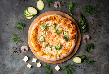 Vegetable pizza with seafood and zucchini on a dark background. Ingredients around. Top view.