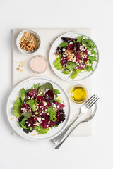 Beetroot salad with feta cheese and walnuts. Vegetable salad in plate on white background, top view