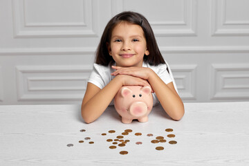 Little child girl with piggy bank at home