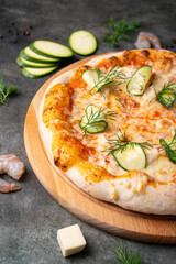 Vegetable pizza with seafood and cheese on dark background. Ingredients around.