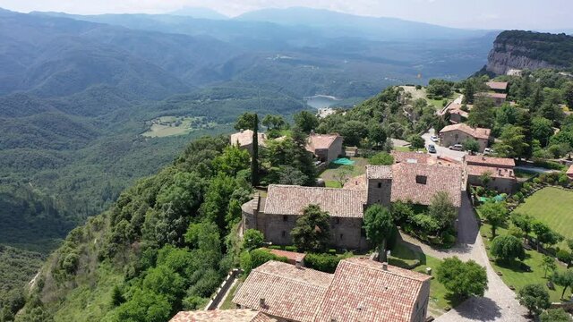 Picturesque green summer landscape with ancient stone buildings of Tavertet town on top of cliff, Collsacabra, Catalonia, Spain. High quality 4k footage