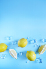 Frame, lay out ice cubes, lemons  and water drops on the blue background. Summer vibes. Cooling fresh humid template composition. Empty space for text on the top. Flyer, card, invitation.