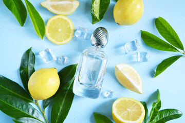 Glass transparent bottle of perfume with yellow lemons, ice cube, water drops and green tree...