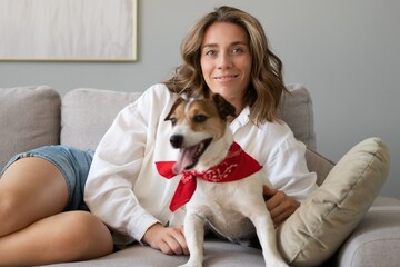Young woman and her dog on sofa at home. Adorable pet.