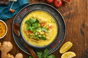 Chicken tikka masala. Traditional of indian cuisine curry and ingredients on dark background. Curry, lime, ginger, cilantro, chili, rice, herbs and spices. Top view with copy space.