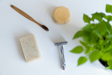 Zero waste product, close up caption. Bamboo toothbrush, solid shampoo, metal razor and solid hand soap. Sustainable bathroom products on a white background.
