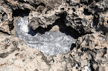 the sea coast in the form of bottom sediments flooded with seawater with the formation of salt patterns and sea lagoons in the form of textures and stone abstractions under water with shadows from the