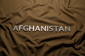 the word afghanistan laid with silver metal letters on crumpled tan khaki canvas fabric