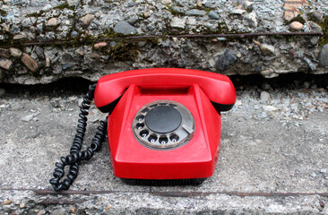 Red old rotary dial telephone on concrete background