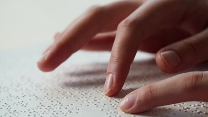 Touching letters on sheet of paper close-up, blindman reading braille book using his fingers, poorly seeing person learning to read, disabled people concept. 
