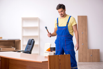Obraz na płótnie Canvas Young male carpenter repairing desk in the office