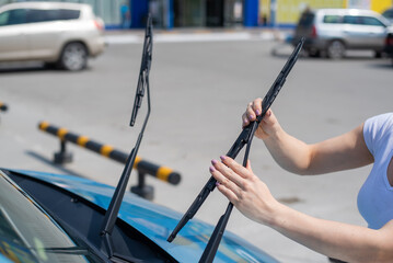 Faceless woman changing car windshield wipers.