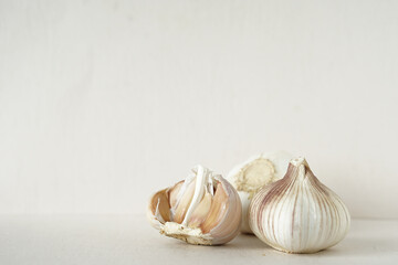 garlic bulb and garlic cloves placed on beige background against beige wall with copy space.