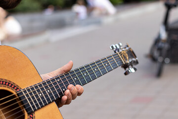 a man's hand plays a chord on an acoustic guitar. close-up. outdoors