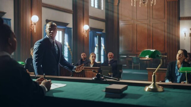 Court of Justice and Law Trial: Male Public Defender Presenting Case, Making Passionate Speech to Judge, Jury. African American Attorney Lawyer Protecting Client's Innocents with Supporting Argument.
