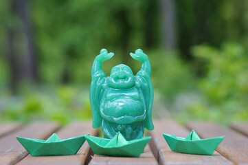 A green figure of a happy Buddha. A religious symbol.