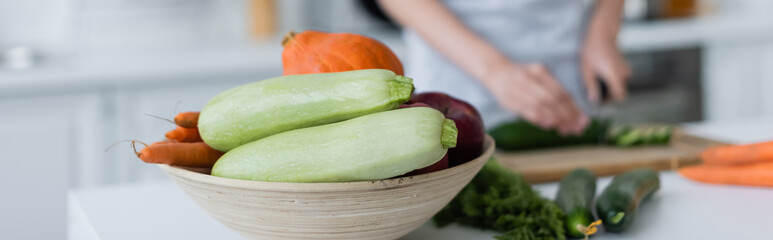 selective focus of bowl with fresh vegetables near blurred woman preparing breakfast, banner.