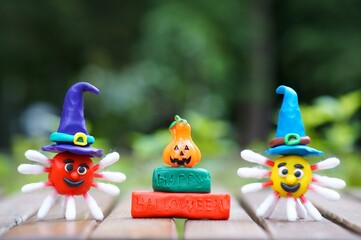 A figure of a virus made of plasticine in a festive hat. Next to the inscription happy Halloween and a pumpkin. The concept of Halloween. Close-up.