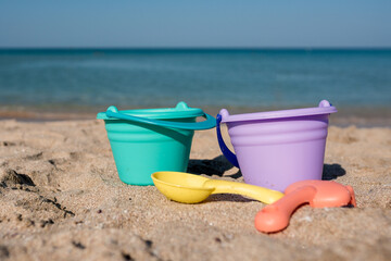 Fototapeta na wymiar Shovels and buckets on coast sea background. Beach toys for family vacation