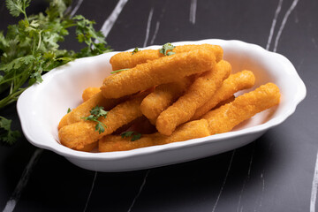Chicken nuggets sticks in a cup on black background.