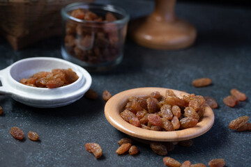 dried green raisins in wooden plate on black background