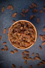 dried green raisins in wooden plate on black background