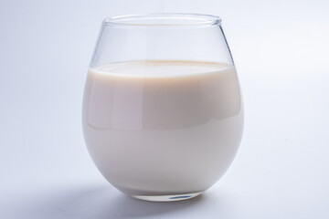 fresh milk in a clear glass on a white background