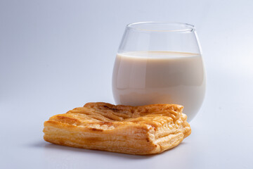 Pineapple pie with fresh milk in a clear glass on a white background.
