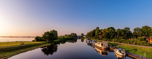 Sonnenaufgangs Panorama am See in Bederkesa. Brücke zwischen See und Kanal. Schiffe am Kanal, die...