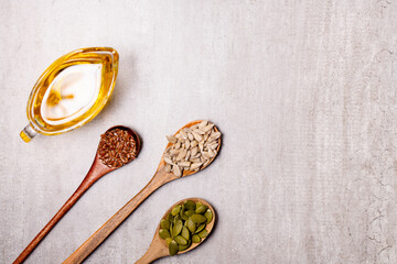 Pumpkin, sunflower, flax seeds on wooden spoons and oil in a glass vessel. Vegetable oils concept....